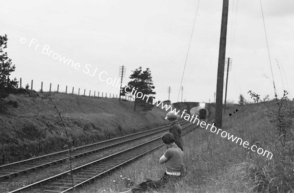 BOYS WATCHING AND WAITING AT RAILWAY EMBANKMENT